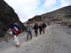 a group of people walking up a dirt road