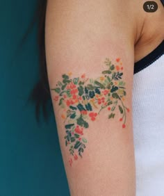 a woman's arm with flowers and leaves tattooed on the left side of her arm