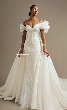 a woman in a white gown with feathers on her shoulders and arms, posing for the camera