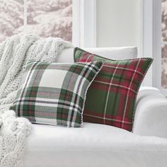 a white couch with two plaid pillows on it