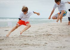 two young boys playing with a frisbee on the beach