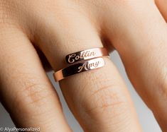 a close up of a person's hand wearing a ring with the word colin on it