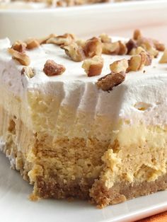 a piece of cake with white frosting and nuts on top sitting on a plate