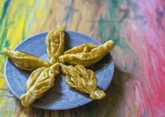 three pieces of dried gourmet food on a blue plate with colorful paint in the background