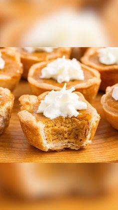 a wooden tray topped with mini pies covered in whipped cream