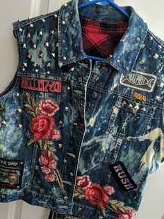 a denim vest with flowers and patches on it hanging from a door handle, in front of a white door