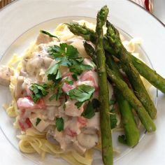 asparagus and pasta on a white plate with parsley garnishes