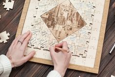 a person holding a pencil and drawing on a jigsaw puzzle with other pieces