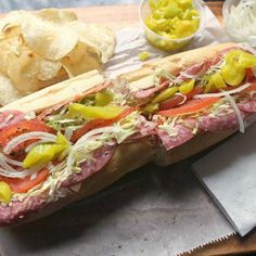 a sub sandwich on a cutting board with potato chips