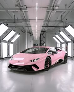 a pink sports car parked in a large room with lots of windows on the ceiling