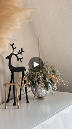 a white shelf topped with two wooden deer figurines next to a potted plant