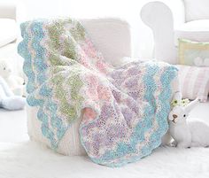 a crocheted blanket sitting on top of a chair next to a stuffed animal