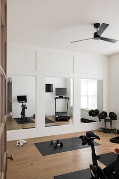 a gym with mirrors, exercise mats and equipment on the floor in front of them