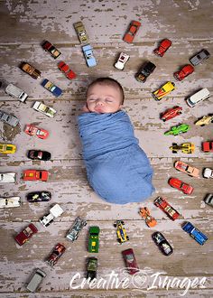 a baby wrapped in a blue blanket surrounded by toy cars on a wooden floor with the words cuddle and images written below it