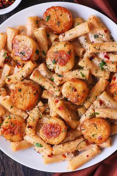 a white plate topped with pasta covered in sauce and meatballs next to a red cloth