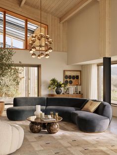 a living room filled with lots of furniture next to large windows on top of a wooden floor