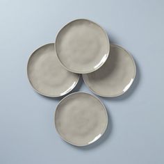 four white plates sitting on top of each other in front of a blue wall and floor