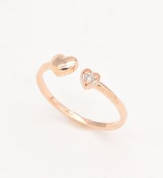 a gold ring with two hearts on the front and one diamond in the middle, against a white background