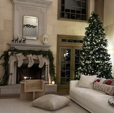 a living room filled with furniture and a christmas tree in front of a fire place