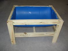 a wooden table with a blue plastic pool in it's center and legs on the floor