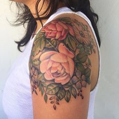 a woman's arm with roses on it and leaves around the arm, in front of her