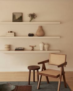 two wooden chairs sitting on top of a rug next to a shelf filled with vases