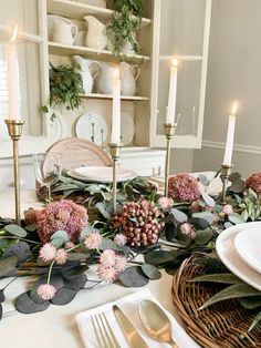 the table is set with flowers, candles and plates for dinner guests to sit at