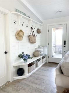 an instagram photo of a bedroom with white walls and wood floors, hanging hooks on the wall