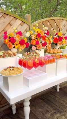 there are many drinks on the table with flowers in vases and plates full of food