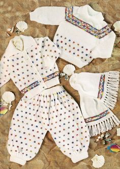 baby clothes laid out on the sand with seashells around them