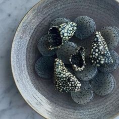 a bowl filled with black and white flowers on top of a table