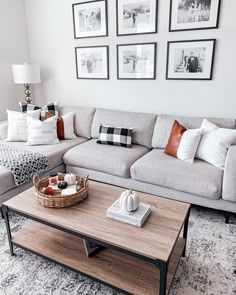 a living room with couches, coffee table and pictures on the wall above it