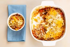 a casserole dish with meat and cheese in it next to a blue napkin