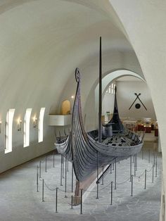 an old boat is on display in the middle of a room with white walls and arched ceilings