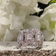 a diamond ring sitting on top of a rock next to white flowers