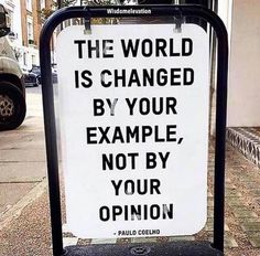 a sign on the sidewalk that says, the world is changed by your example not by your opinion