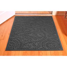 a black door mat on the floor in front of a white wall and wooden floors