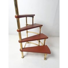 a three tiered wooden shelf with gold metal legs and brown leather top, against a white background