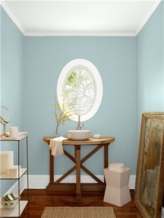 a bathroom with blue walls and wood floors, including a round window in the corner