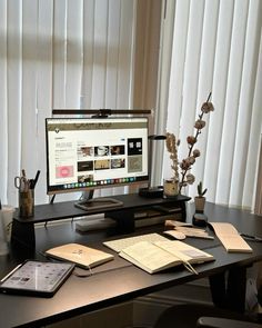 a computer monitor sitting on top of a desk next to a keyboard and notebooks