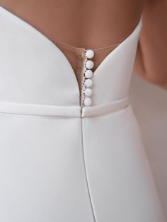 the back of a woman's white dress with buttons