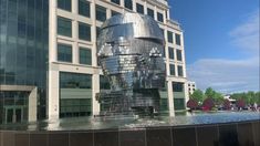 a water fountain in front of a large building with lots of windows on the side