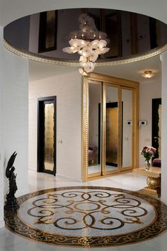 a fancy entryway with an intricately designed rug and chandelier in the center