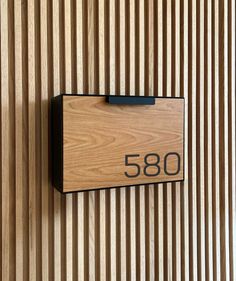 a house number sign mounted to the side of a wooden wall with vertical slats