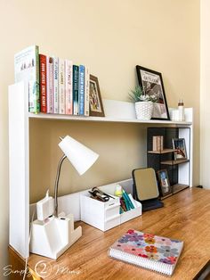 a wooden desk topped with books and a lamp next to a book shelf filled with books