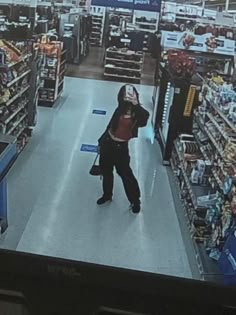 the man is walking through the store with his hand on his head and wearing a hoodie