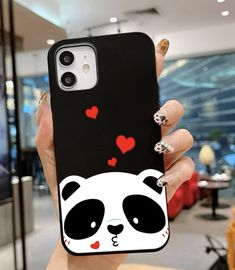 a woman holding up a phone case with a panda face on it and hearts in the background