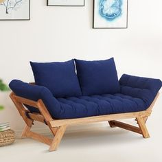 a blue futon couch sitting in front of three framed pictures