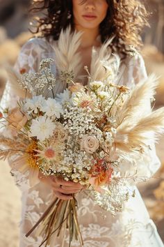 a woman in a white dress holding a bouquet of wildflowers and pamodia