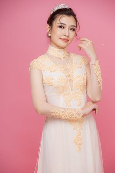 a woman in a white dress with a tiara on her head posing for the camera